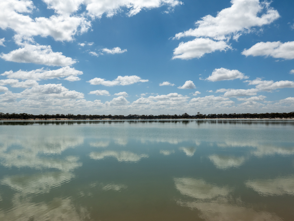 Die Wolken am Himmel spiegeln sich auf der fast glatten Oberfläche des Sees
