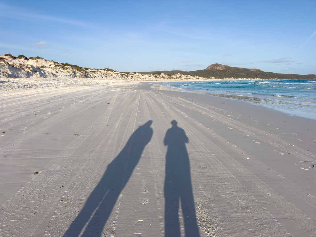 Schattenselfi. Wir sehen viele Reifenspuren im Sand