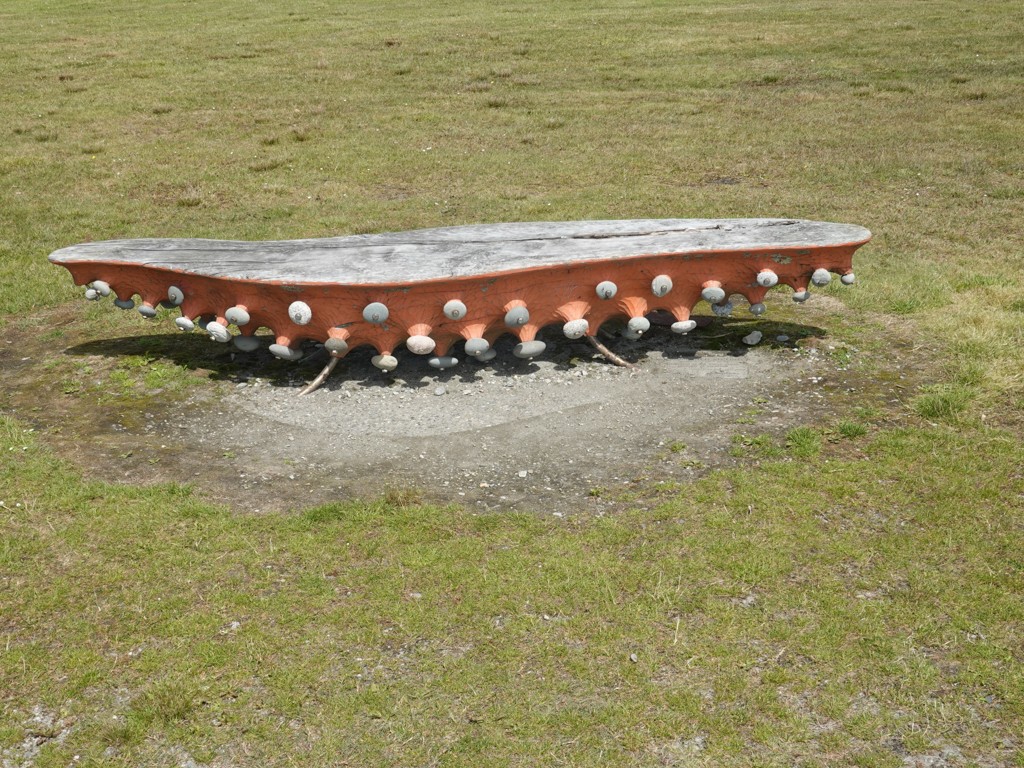 Steinkunst wie Saugnäpfe an einer künstlerischen Holzbank an der Hokitika Beach