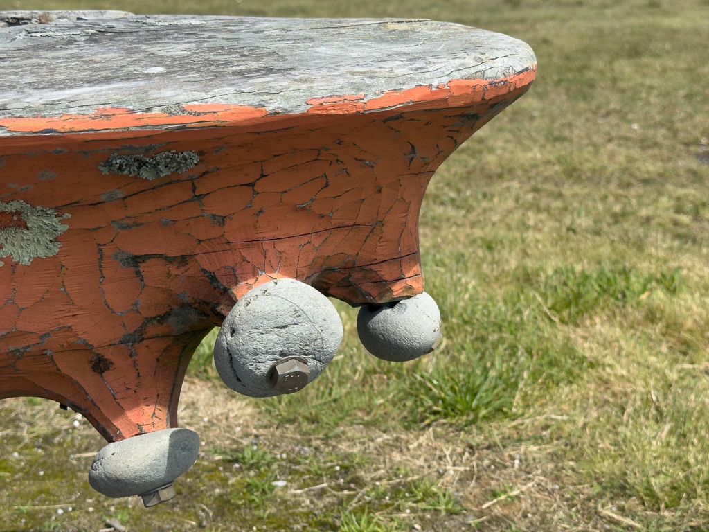 Steinkunst wie Saugnäpfe an einer künstlerischen Holzbank an der Hokitika Beach