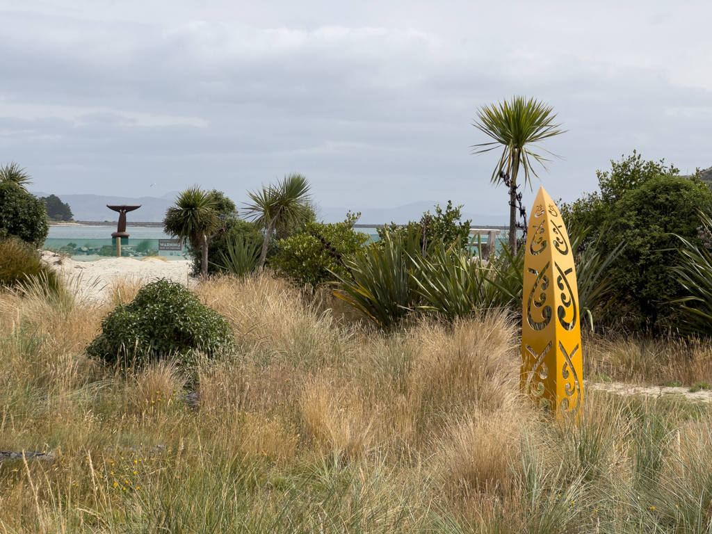 Te Rauone Reserve mit modernen Wahrzeichen; dahinter das Meer