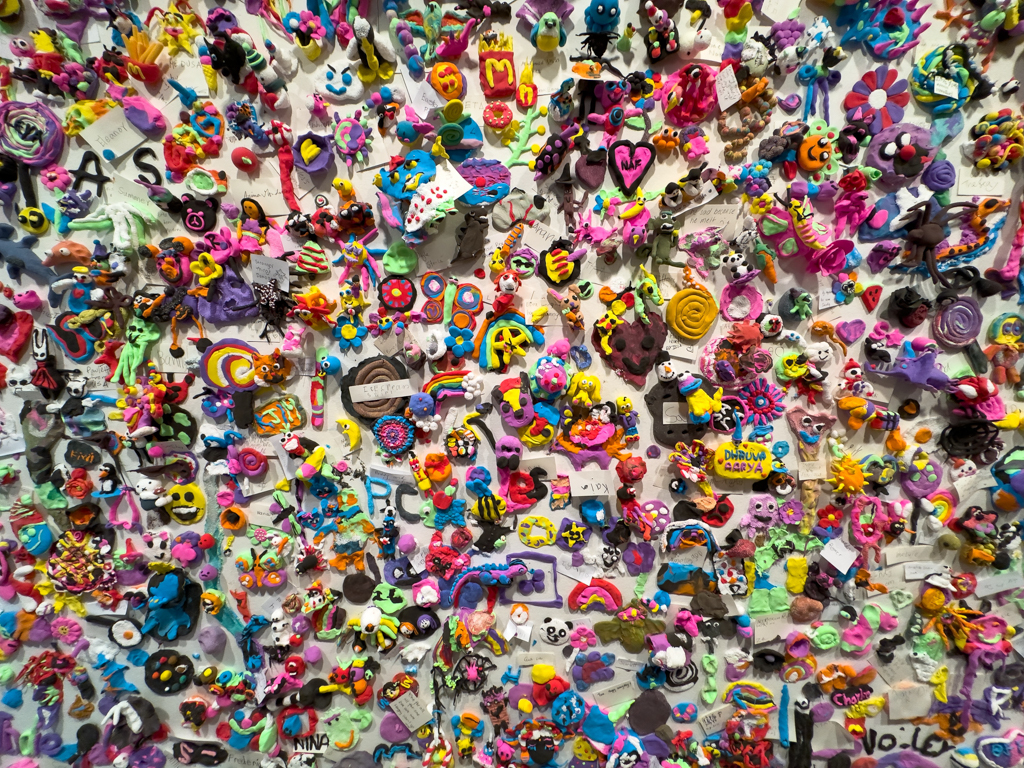 Eine Wand voller kleiner bunter Kunstwerke